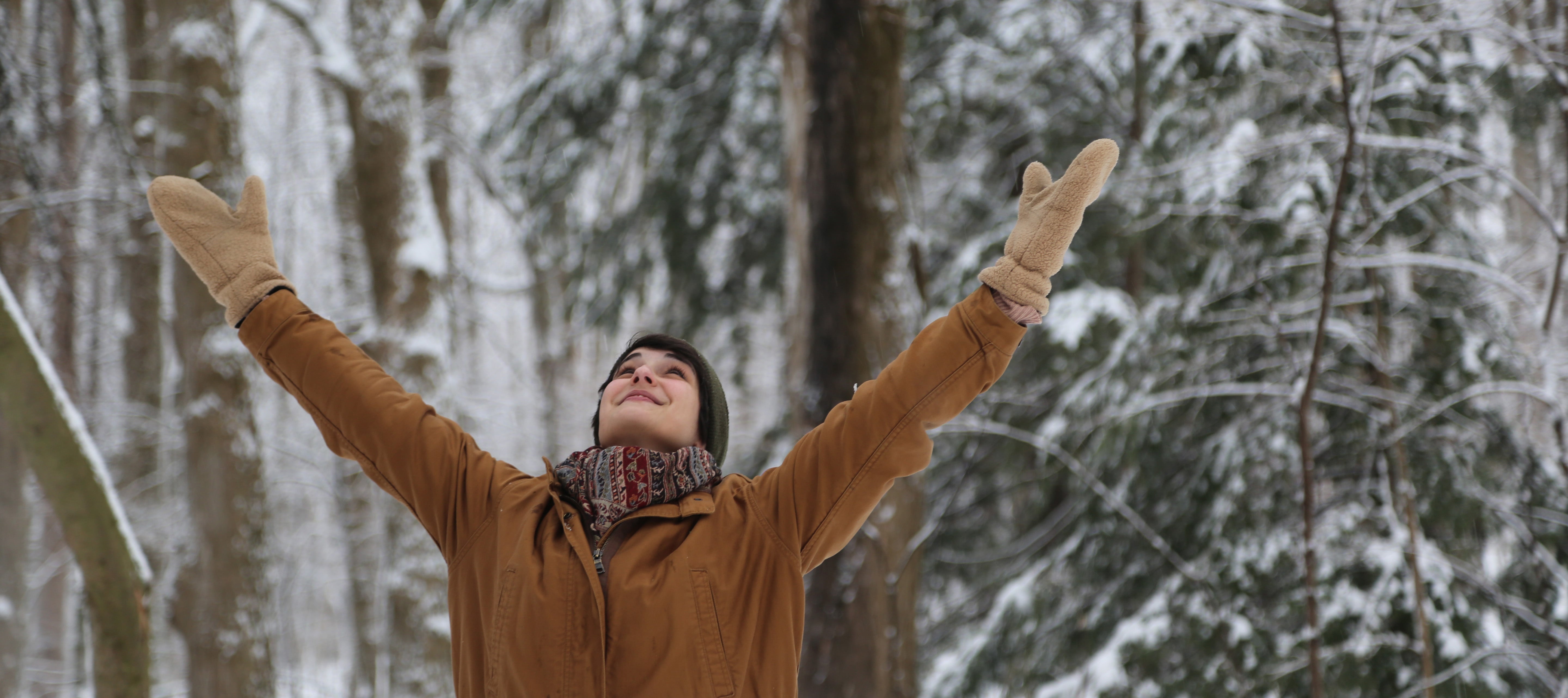 Woman with arms raised in the forest in the winter