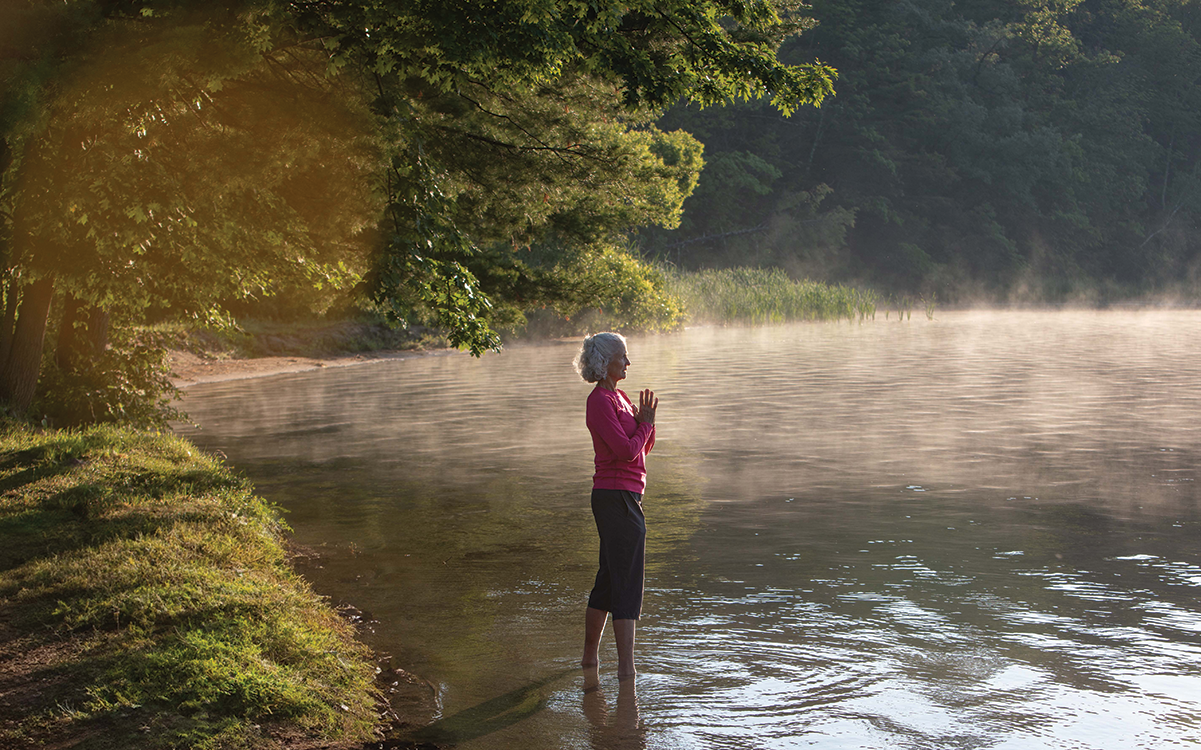 Woman with hands together standing in a lake.