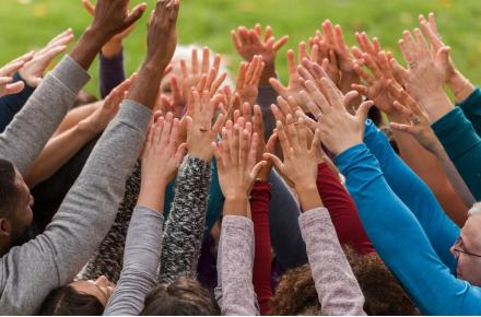 Group of people with hands raised.
