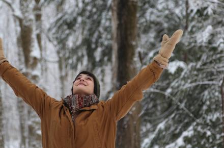 Woman with arms raised in the forest in the winter
