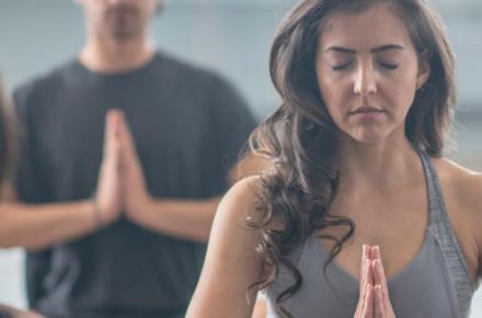 Group of people doing yoga with palms together, eyes closed