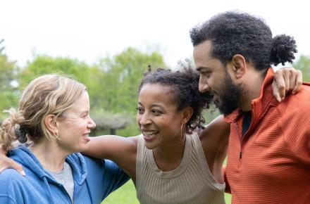 Woman hugging a woman and a man in a huddle