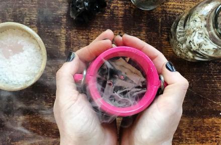 Hands holding a cup with burning incense