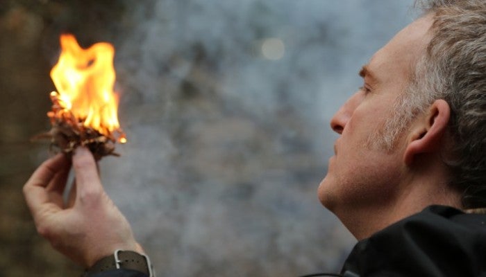 Birthing Fire, Level 1 Micah Mortali holding kindling that is on fire.