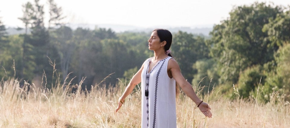 woman with arms outstretched standing in field