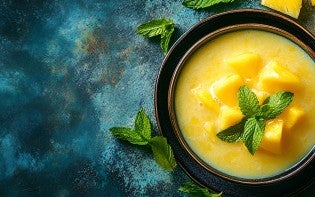 Bowl of chilled mango soup garnished with mint