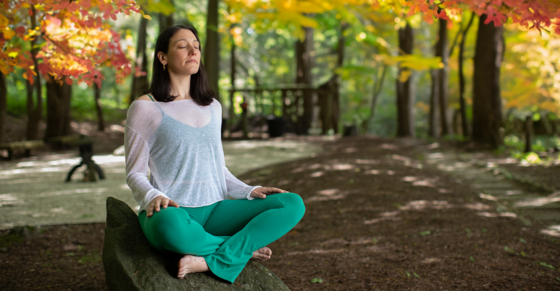 woman sitting outside in the woods meditating
