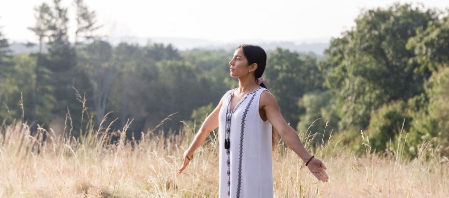 woman with arms outstretched standing in field