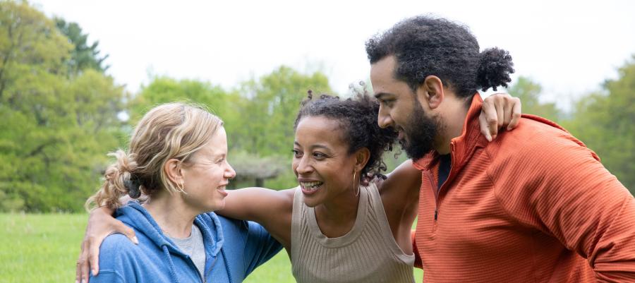 Woman hugging a woman and a man in a huddle