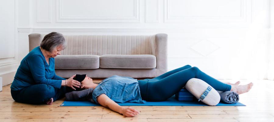 Judith Lasater seated with her hands on the head of a woman lying on her back