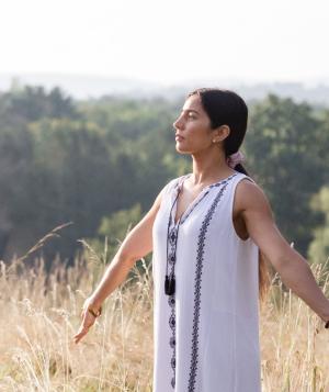 woman with arms outstretched standing in field