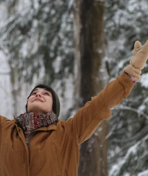 Woman with arms raised in the forest in the winter