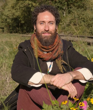 Luis Mojica sitting in a field with grass and flowers.