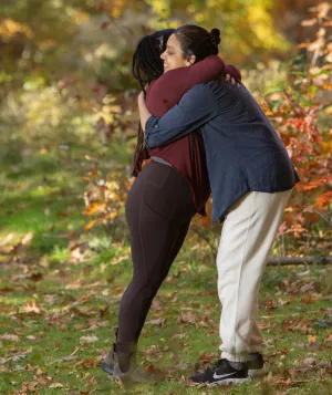 Two women hugging in the woods in the fall.