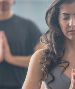 Group of people doing yoga with palms together, eyes closed