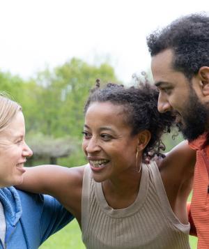 Woman hugging a woman and a man in a huddle